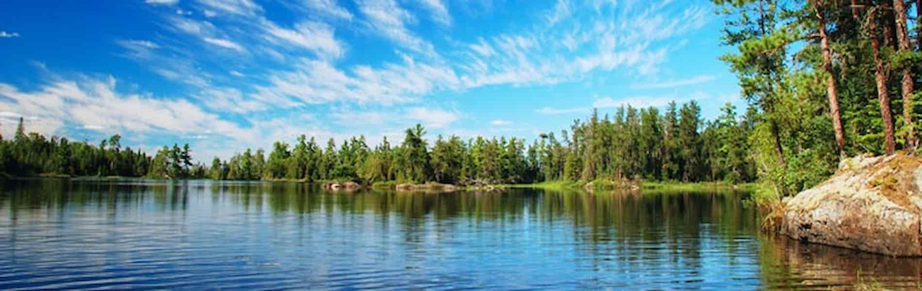 wide-shot-of-lake-on-a-sunny-day-with-pine-shoreline-in-background