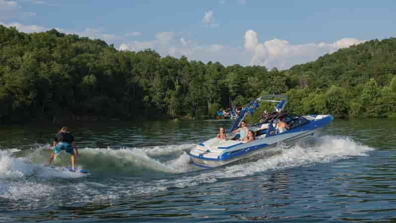image of wake surf boat with surfer behind and people in the boat